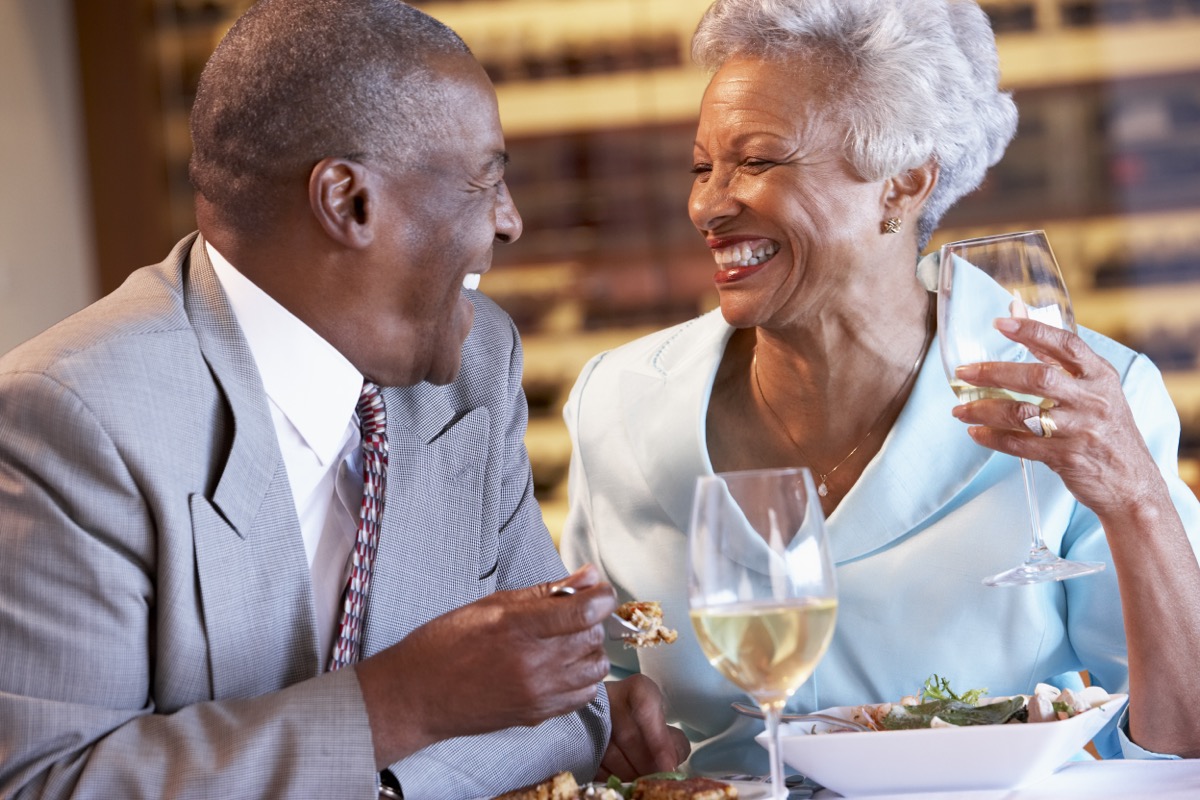 couple de personnes âgées riant en train de dîner